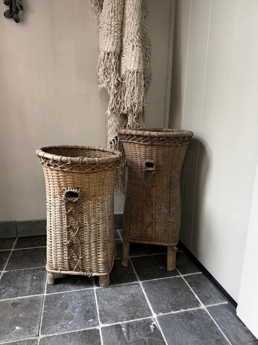 Twee handgemaakte rieten manden met een grof geweven plaid in een sober, landelijk interieur