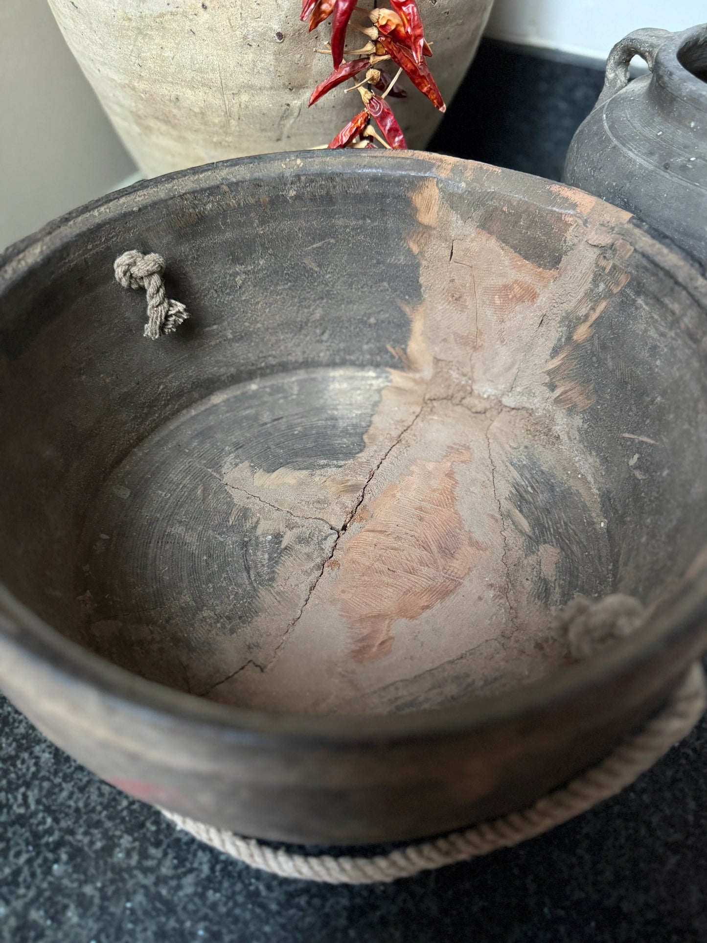 Authentieke, handgemaakte houten bak op zwart aanrecht, landelijke sobere woonstijl