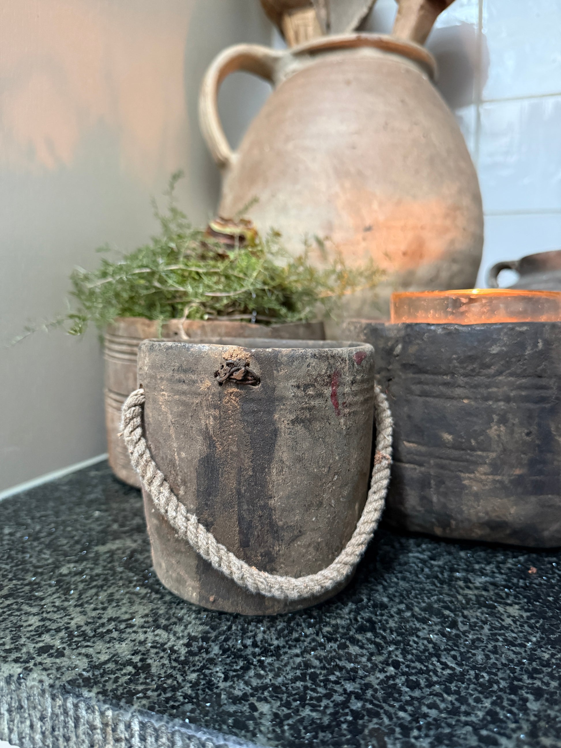 Authentieke handgemaakte landelijke woonaccessoires, houten pot met touw, kruik en plantje op natuurstenen aanrecht bij My Sober Home.
