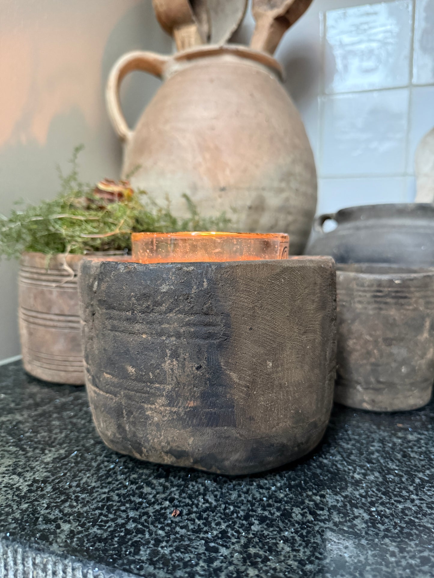 Authentieke handgemaakte landelijke pot met kaars, sobere woonaccessoires op zwarte steen