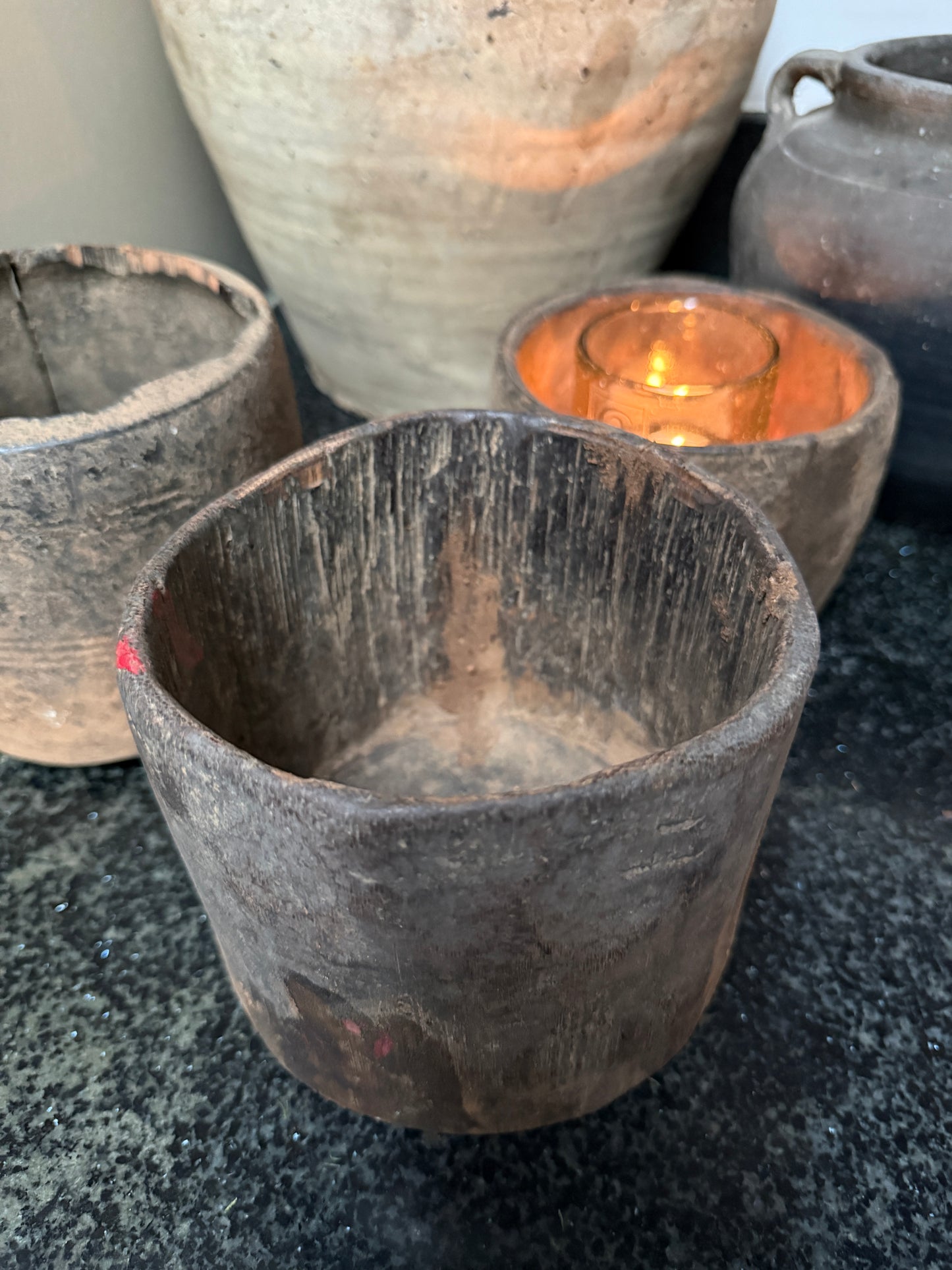 Authentieke handgemaakte houten potten en waxinelichtje op donkere ondergrond, sober interieur