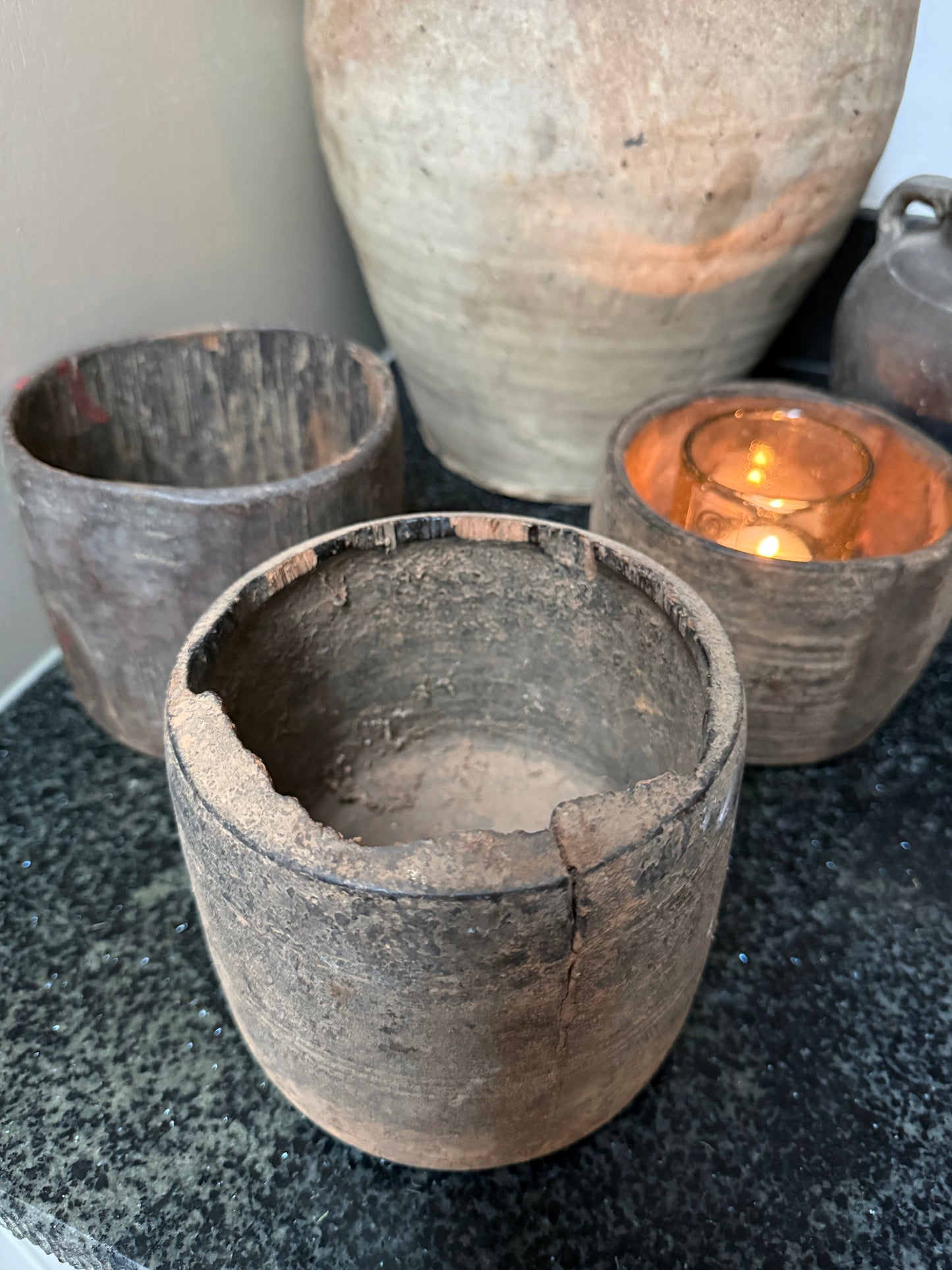 Authentieke, handgemaakte aardewerken potten en windlicht op zwarte ondergrond, sober landelijk interieur