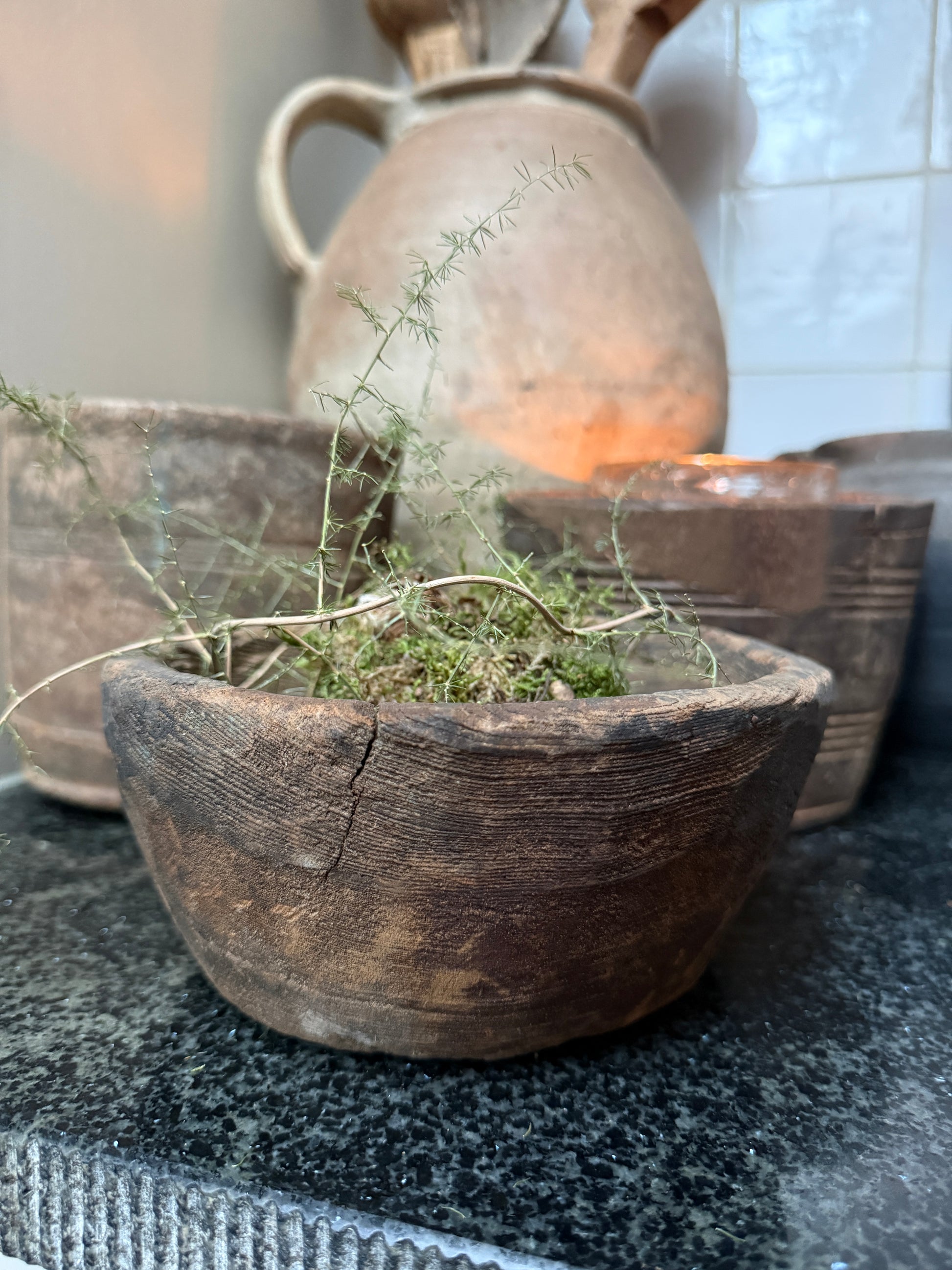 Authentieke houten schaal met groen decor, landelijke en sobere woonaccessoires op aanrecht.