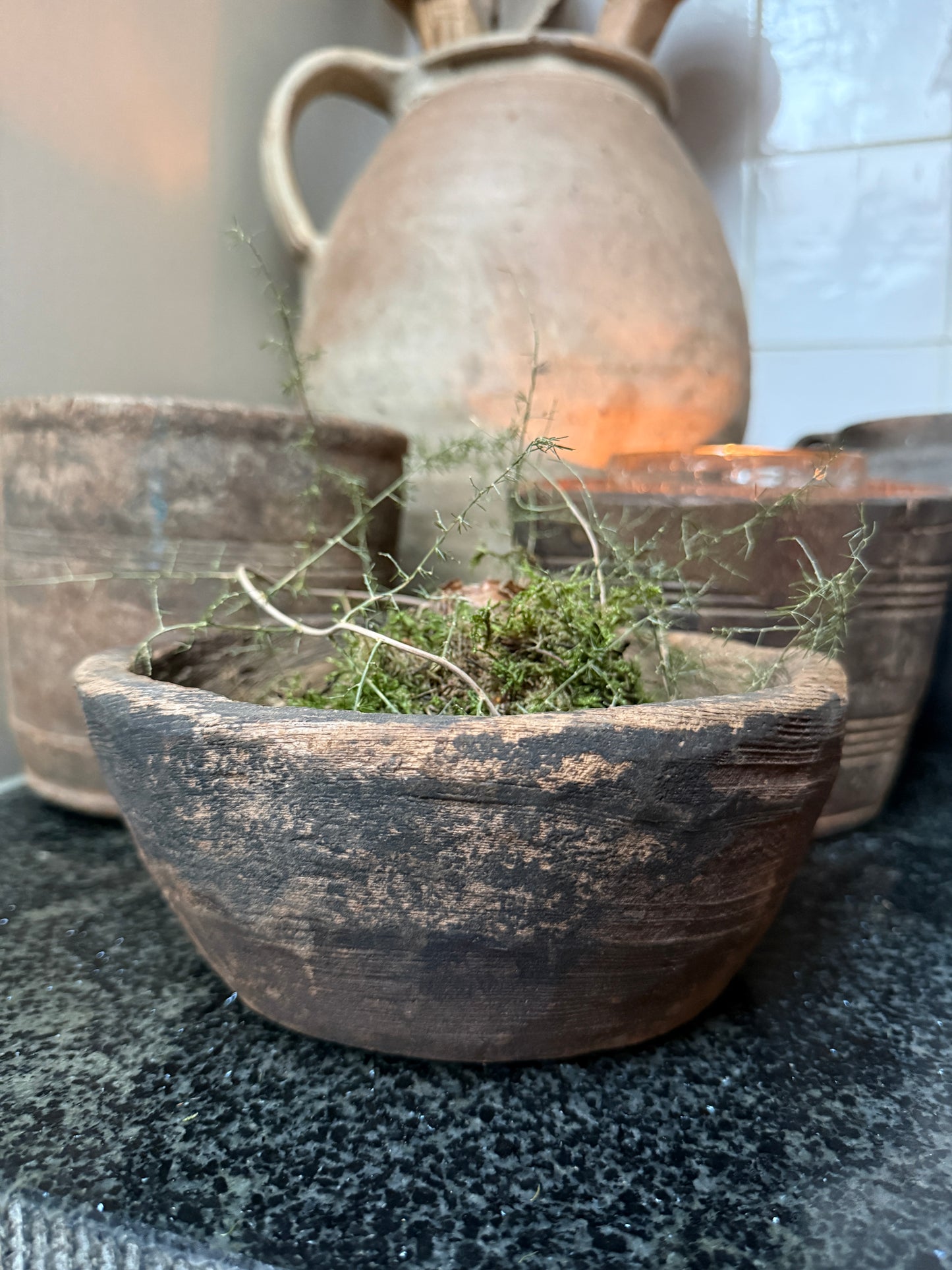 Handgemaakte, rustieke schaal met mos op donkere ondergrond, landelijk sober interieur