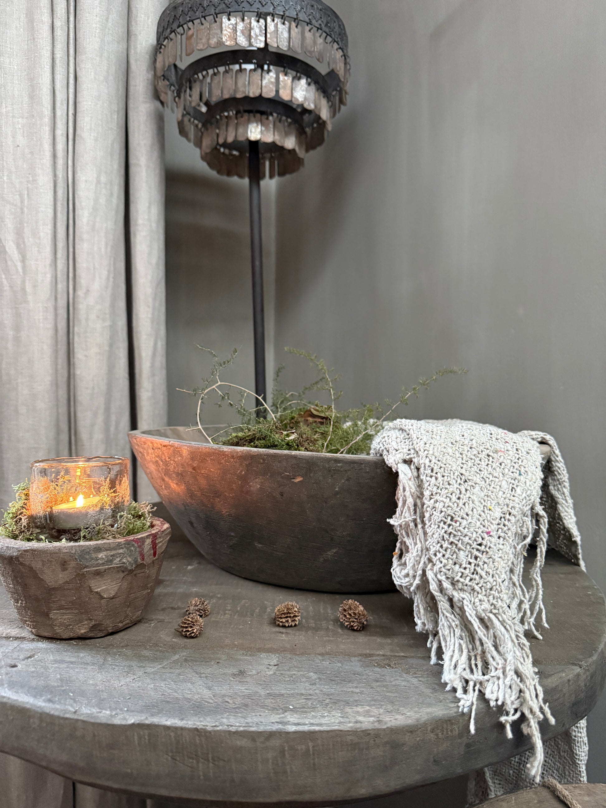 Handgemaakte landelijke woonaccessoires: houten schaal, kaars in stenen pot, stoffen plaid