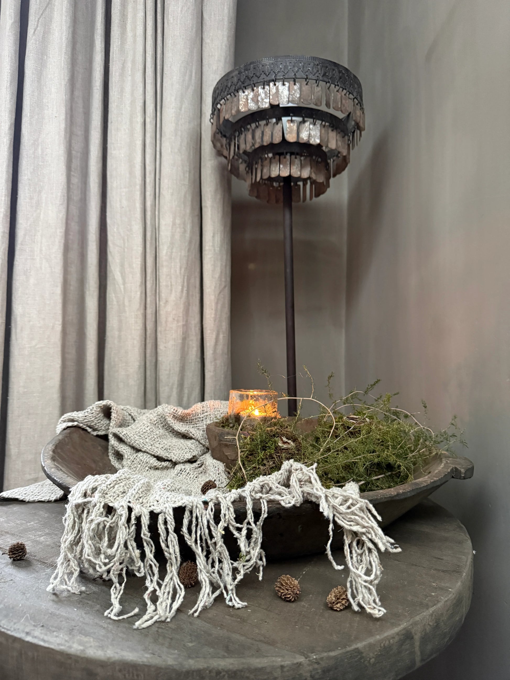 Sober, landelijke woonaccessoires met houten schaal, linnen doek en brandend windlicht op tafel