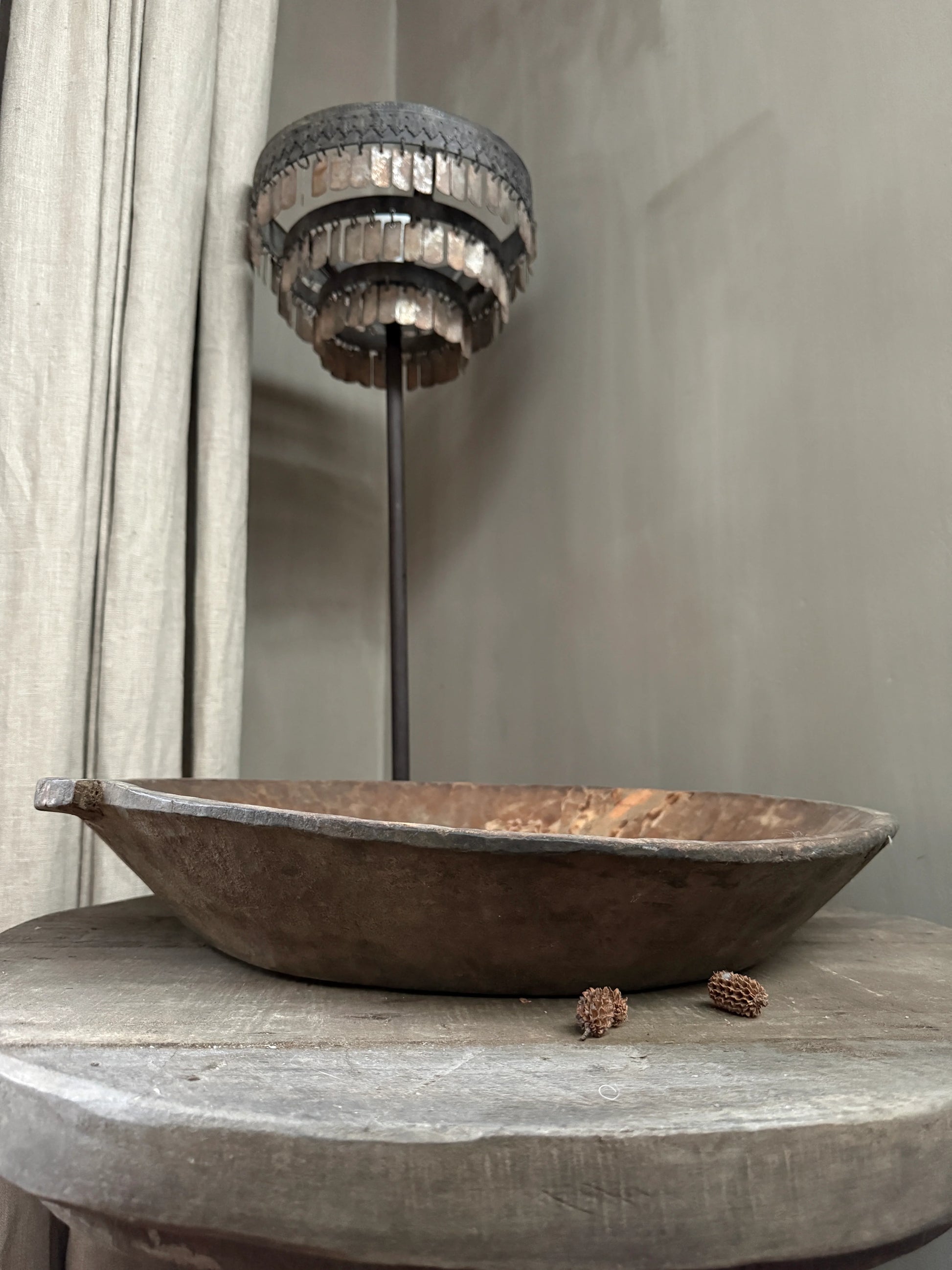 Authentieke, handgemaakte houten schaal op rustieke tafel met sober metalen lamp, landelijk interieur