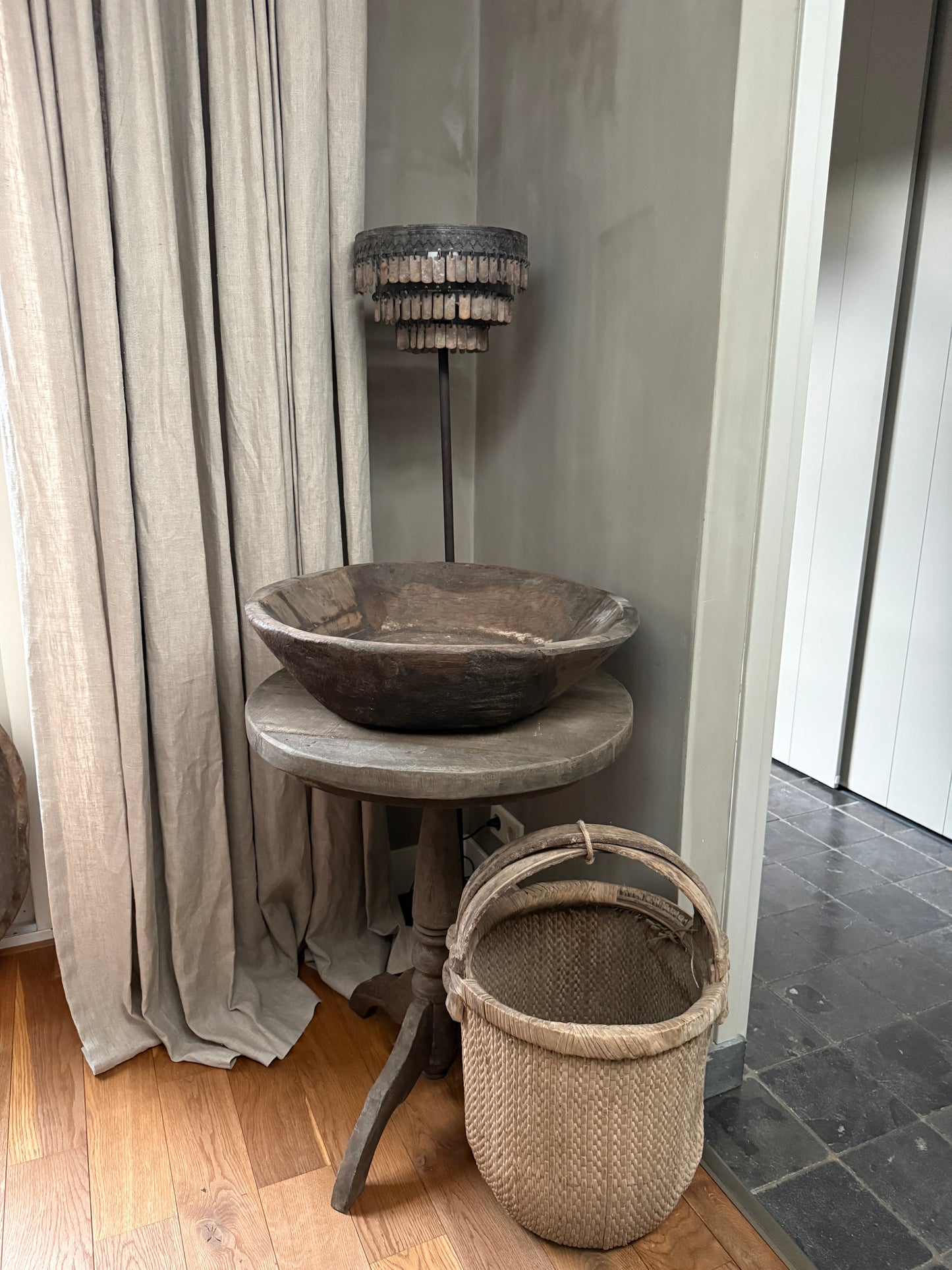 Landelijke handgemaakte woonaccessoires: houten schaal, rieten mand en sfeerlamp in sober interieur