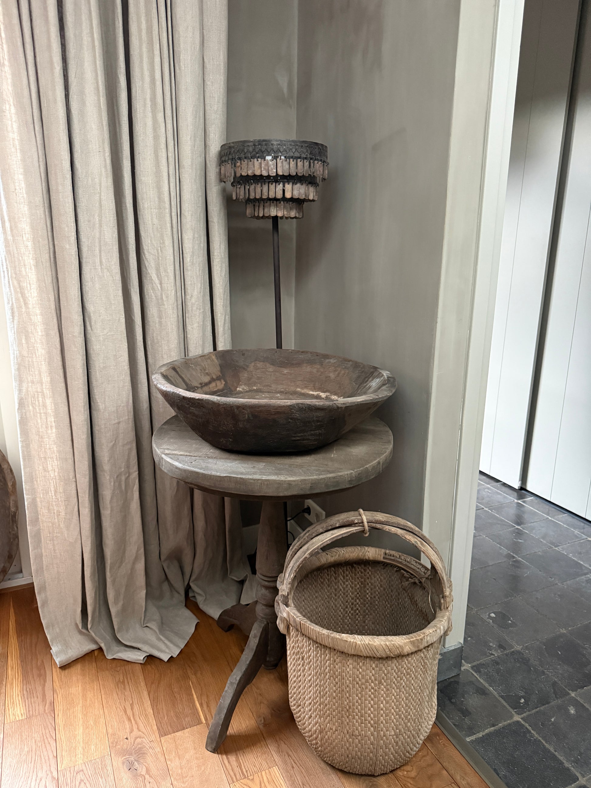 Landelijke handgemaakte woonaccessoires: houten schaal, rieten mand en sfeerlamp in sober interieur