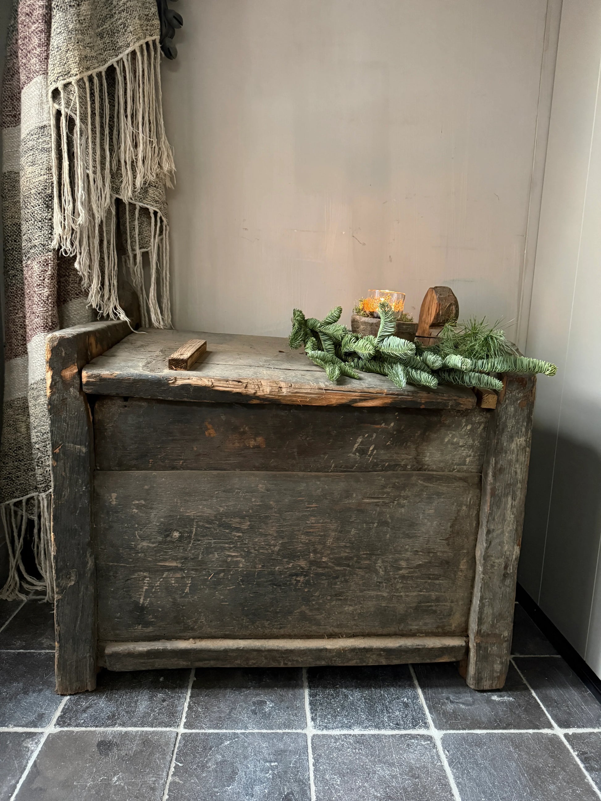 Authentieke landelijke houten kist met groene decoratie en handgemaakte plaid, sober interieur