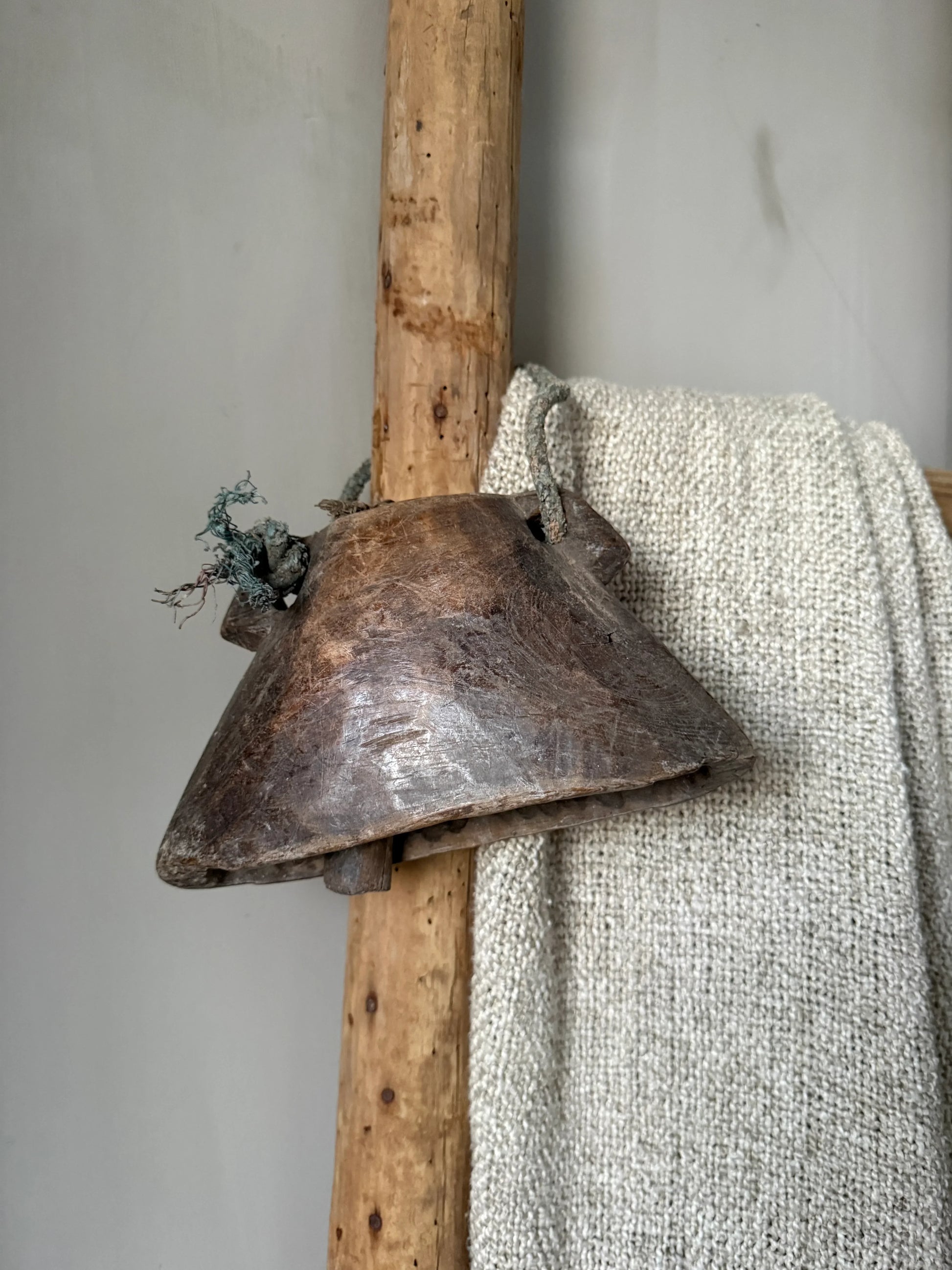 Authentieke houten bel op rustieke ladder met handgemaakt wollen plaid, landelijk interieur