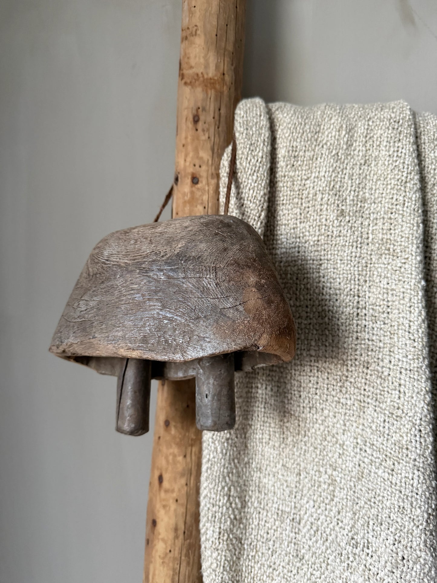 Handgemaakte houten bel aan rustieke stok met wollen plaid, sober interieuraccessoire