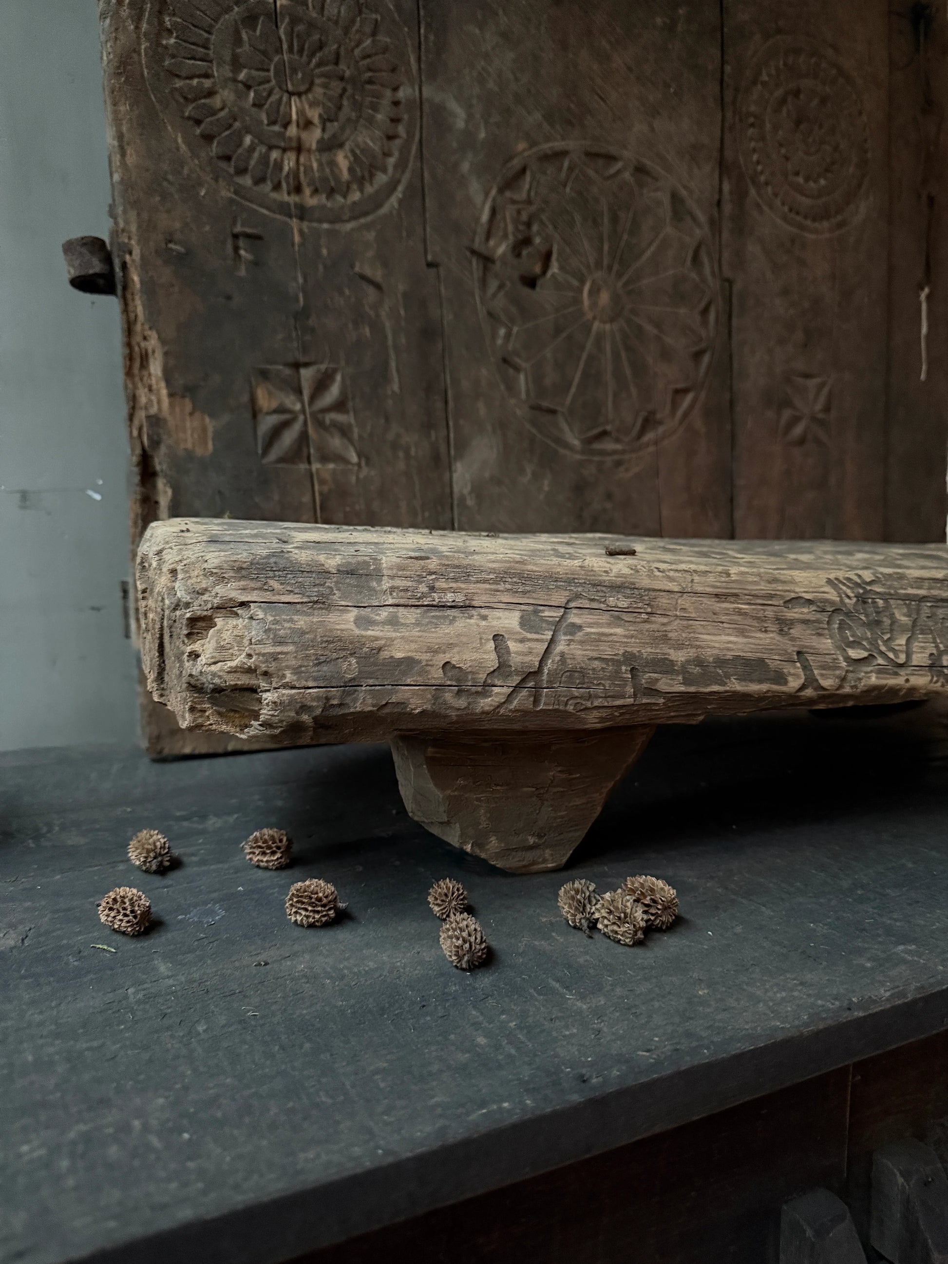 Authentieke handgemaakte houten woonaccessoire met uitgesneden patronen en decoratieve zaden, landelijk en sober interieur