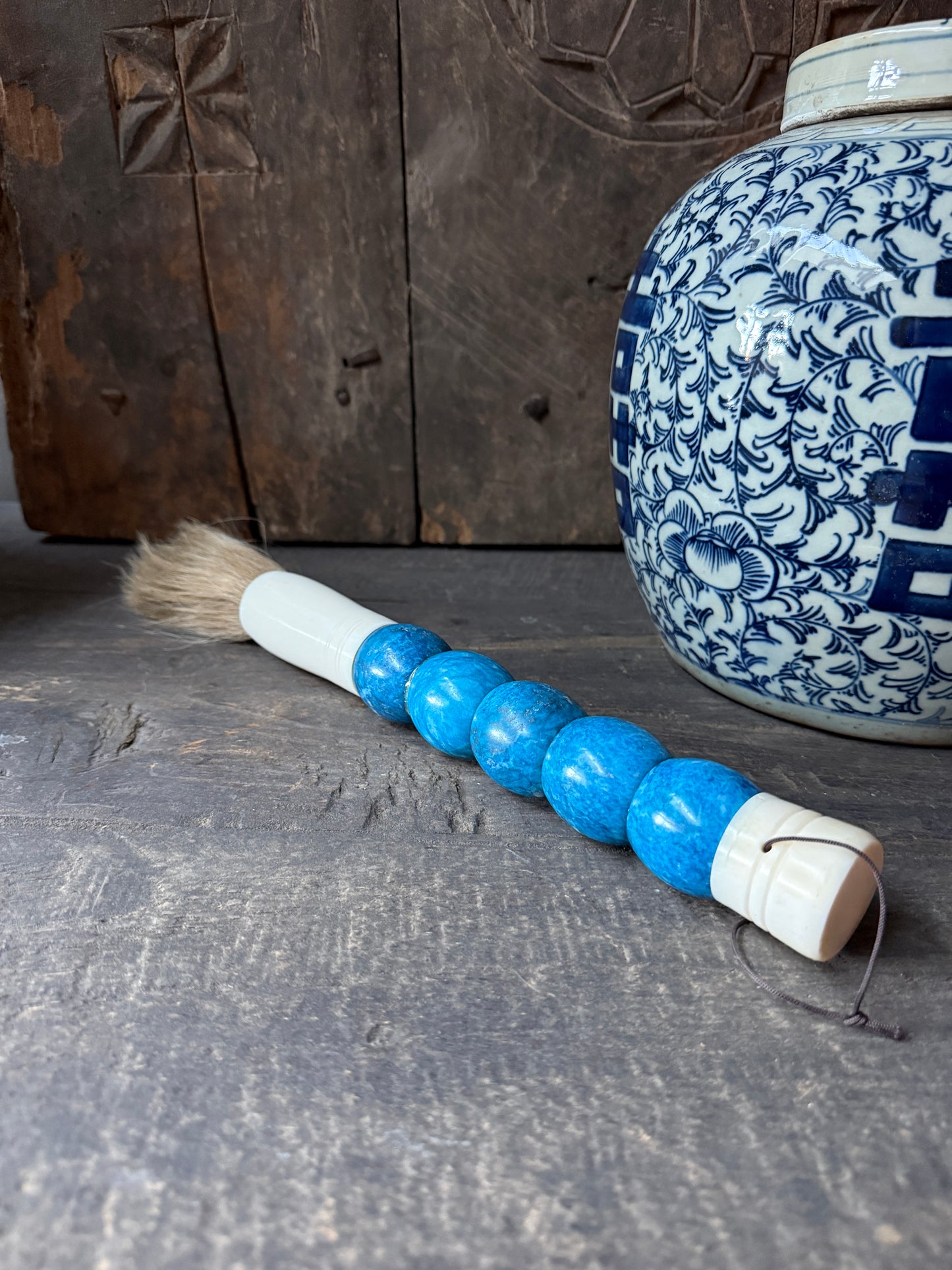 Handgemaakte penseel met blauwe kralen en wit porseleinen doosje, landelijk sober interieur