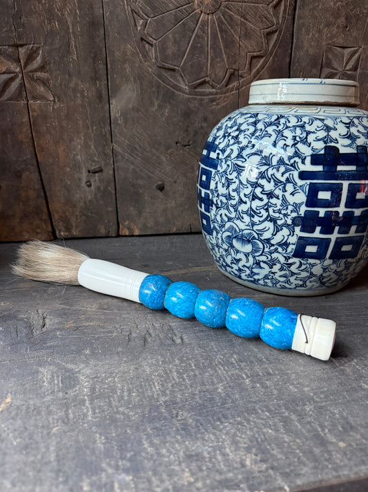 Handgemaakte blauwe kalligrafieborstel en porseleinen pot, sober landelijk interieur