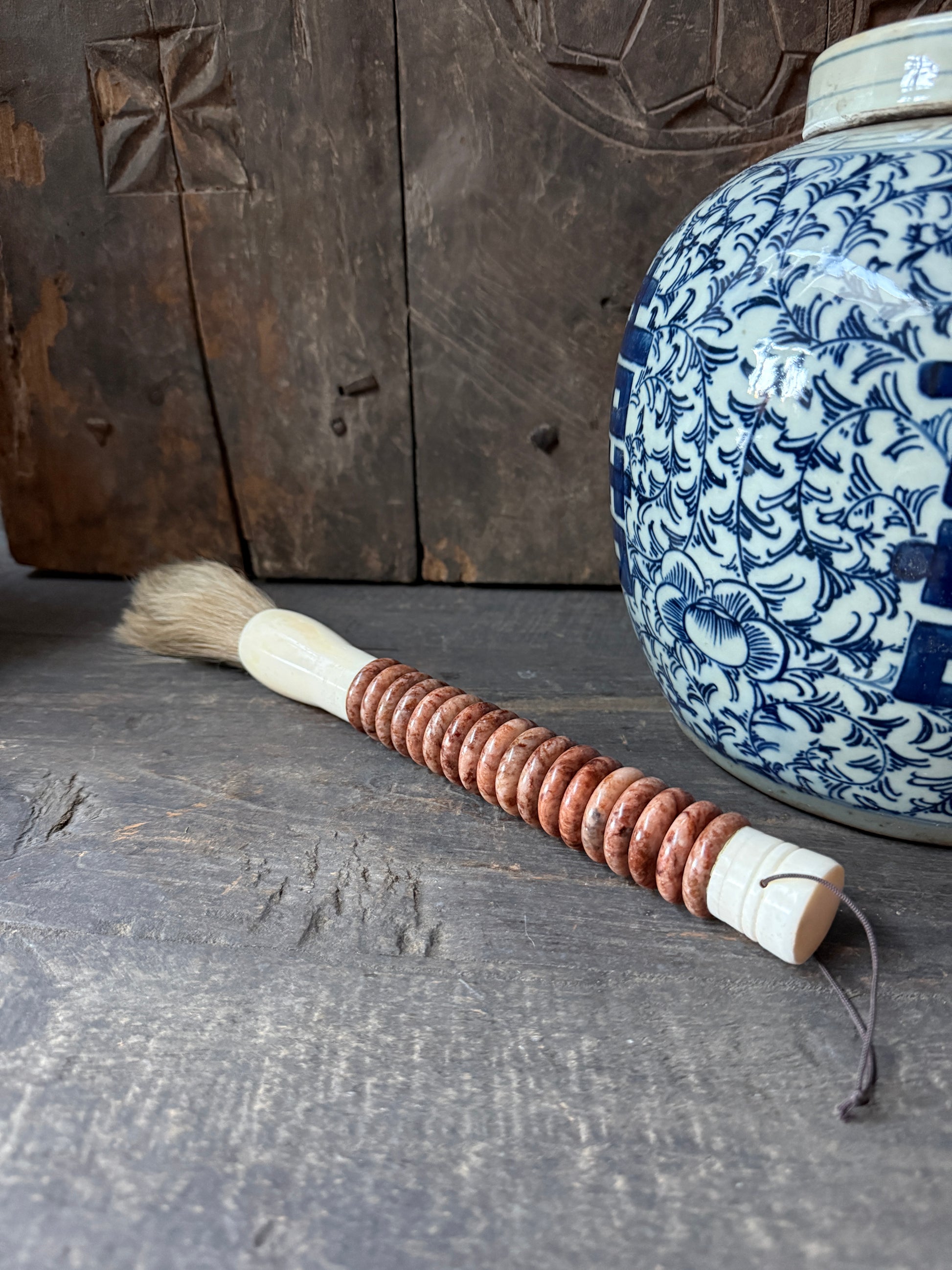 Handgemaakte decoratieve kwast met houten kralen op rustieke tafel, oosters keramiek en sober interieur