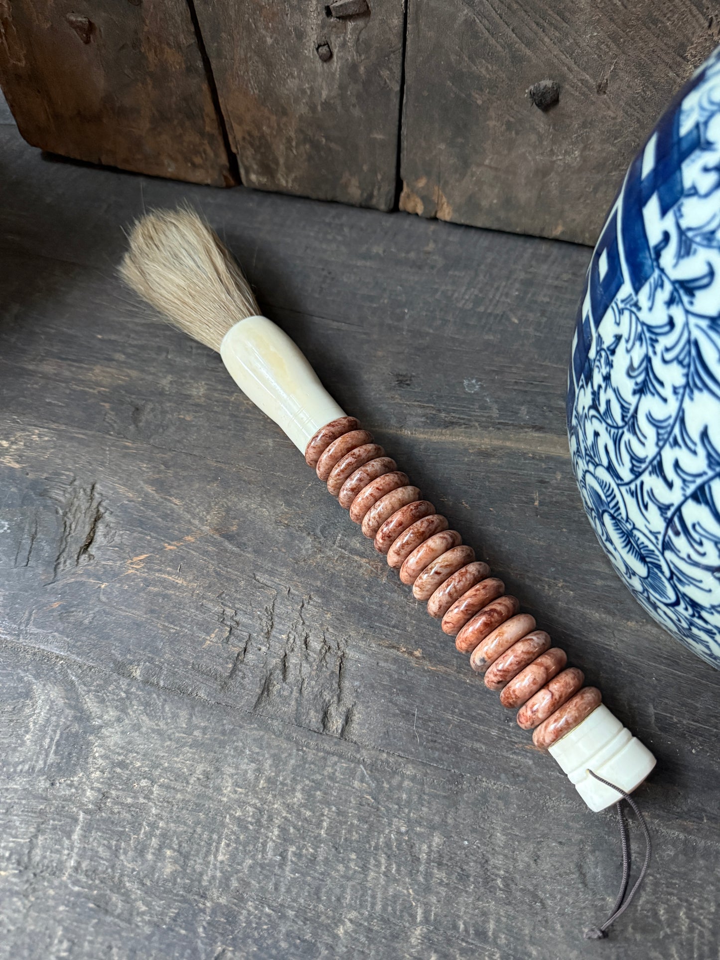 Handgemaakte landelijke kwast met houten kralen op een rustieke houten tafel, My Sober Home