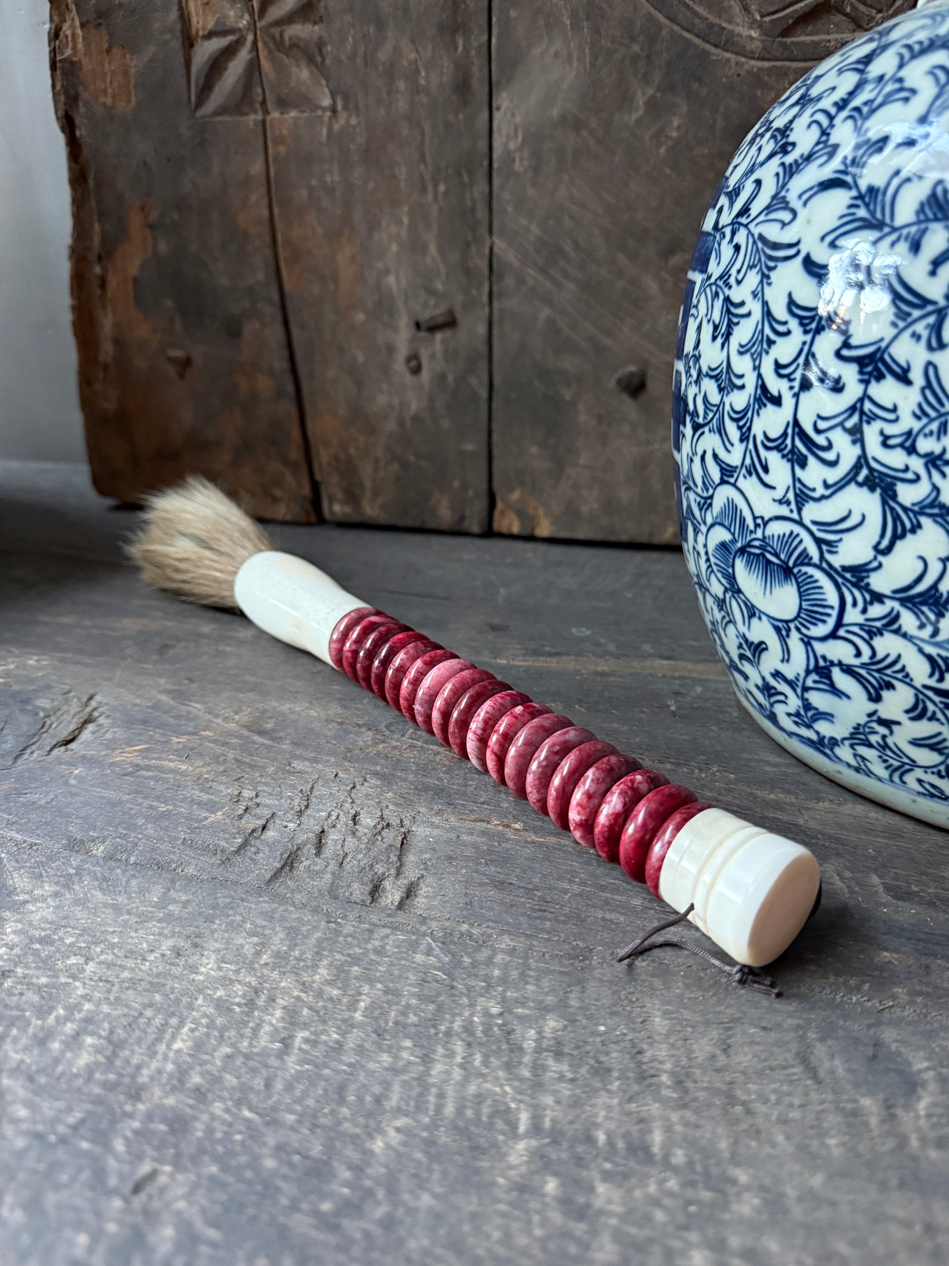 Handgemaakte kalligrafieborstel met rood handvat op houten tafel, landelijke woondecoratie