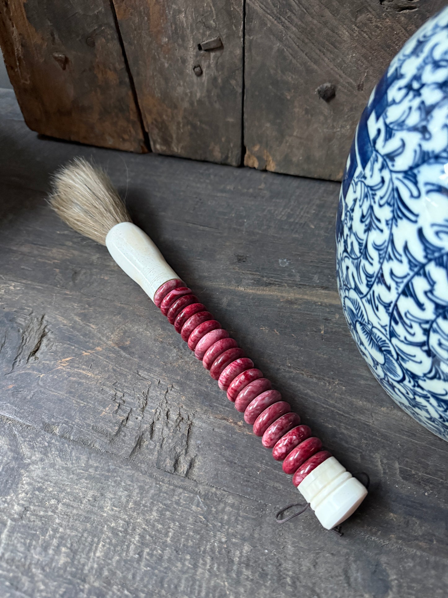 Antieke handgemaakte kwast met rood handvat op houten tafel, landelijke woondecoratie