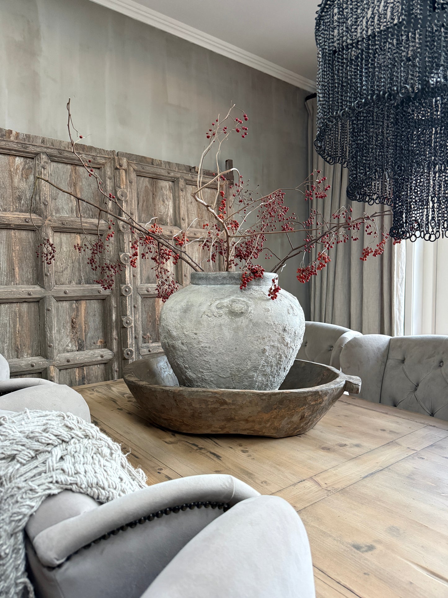 Handgemaakte landelijke vaas met rode bessen op houten tafel, sober interieur My Sober Home