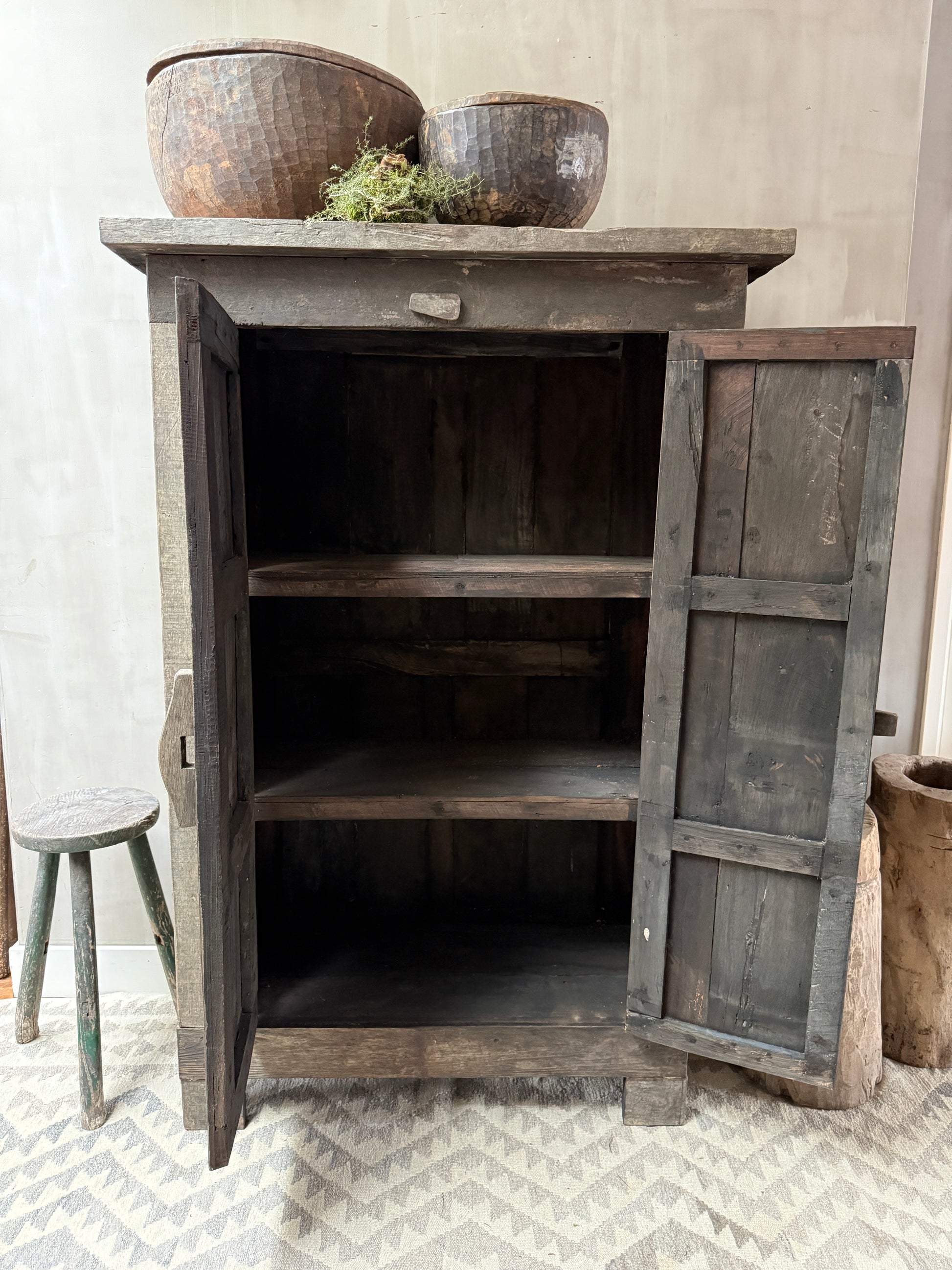 Authenieke houten kast met open deuren, houten kruk, landelijke decoratie en handgemaakte schalen