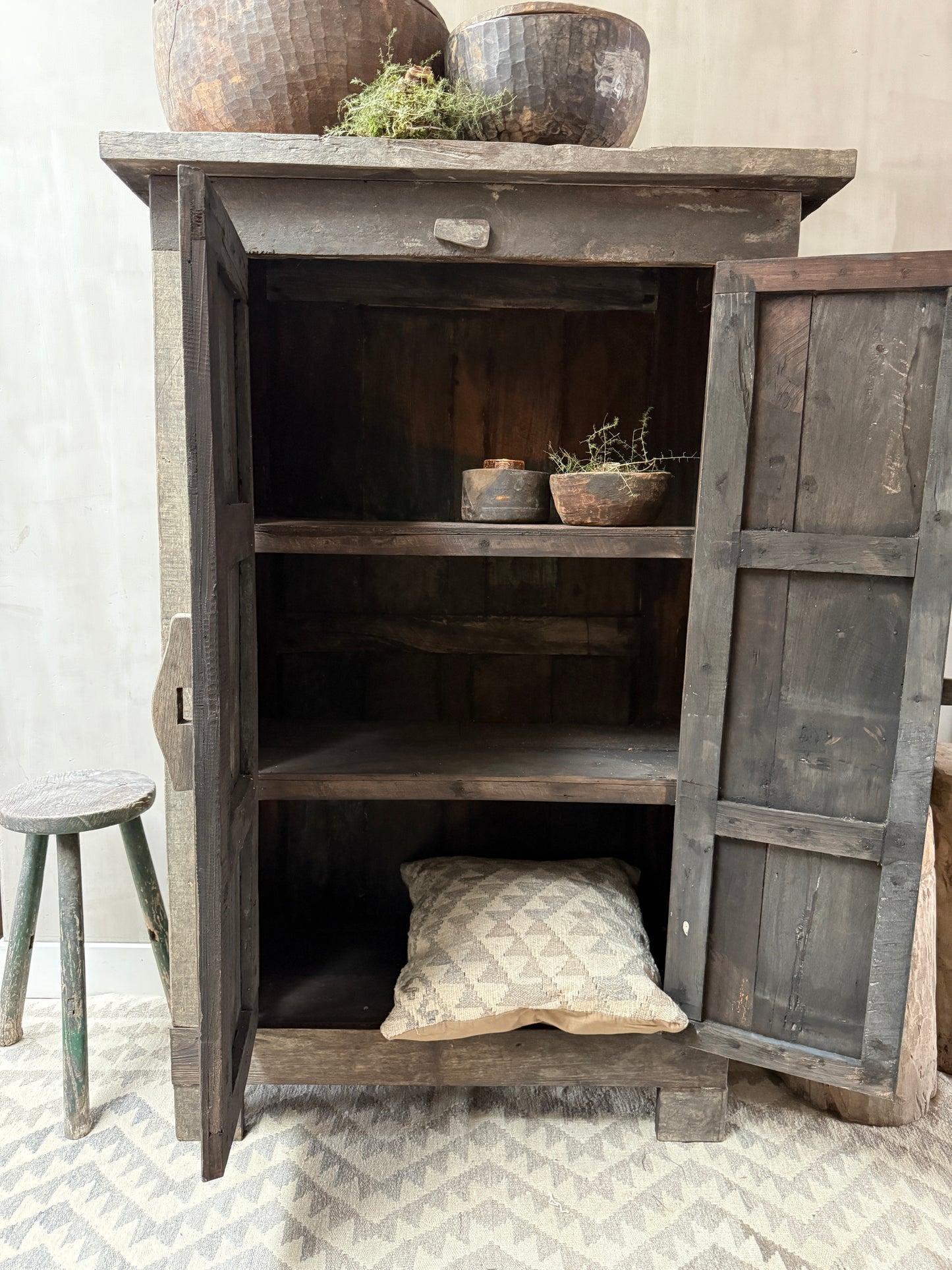 Authentieke houten kast met handgemaakte schalen en kussen, landelijk sober interieur