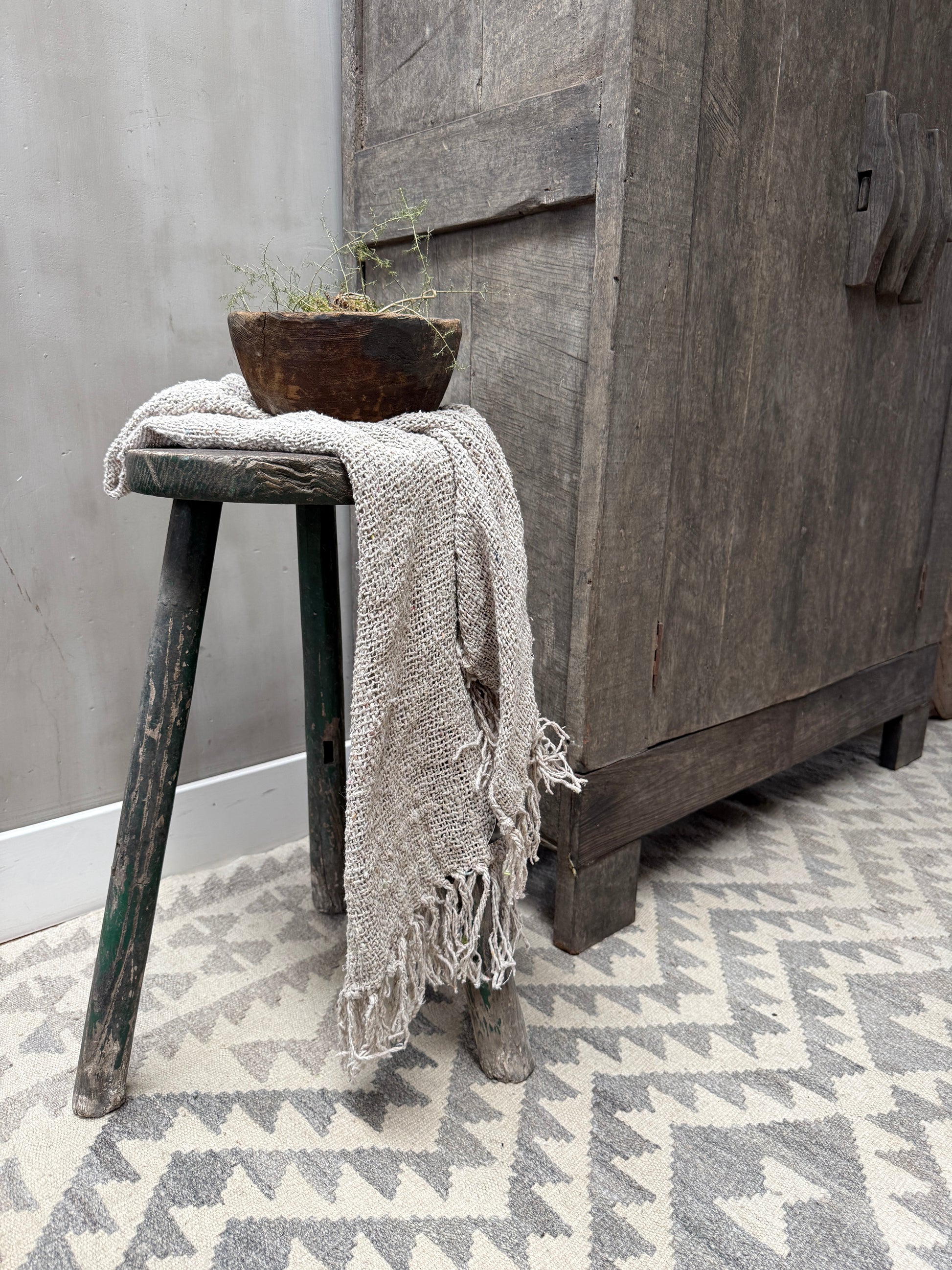 Handgemaakte houten kruk met rustieke schaal en linnen plaid, landelijk sober interieur