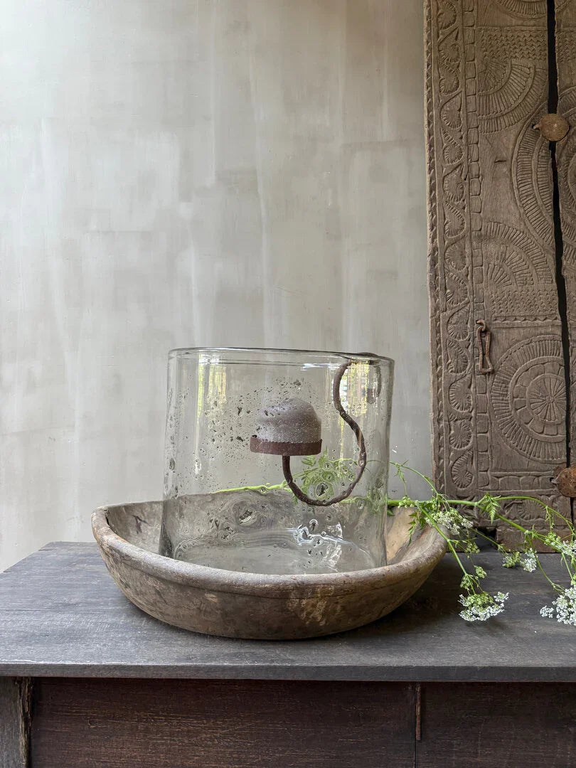 Authentieke glazen windlicht in houten schaal met sobere landelijke decoratie op houten tafel