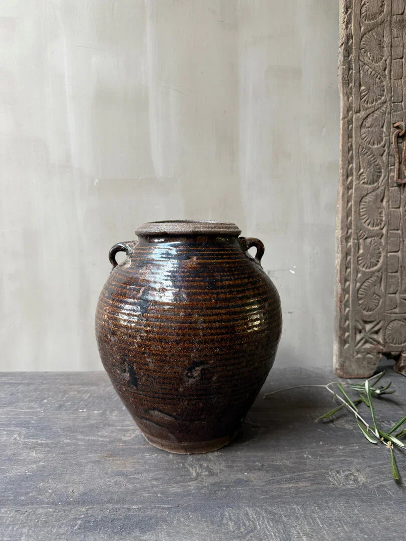 Authentieke handgemaakte bruine aardewerken pot op houten tafel, landelijk en sober interieur