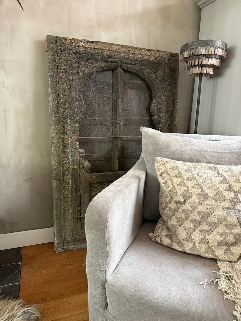 Landelijke woonkamer met grijze bank, vintage houten deur uit India en handgemaakte woonaccessoires