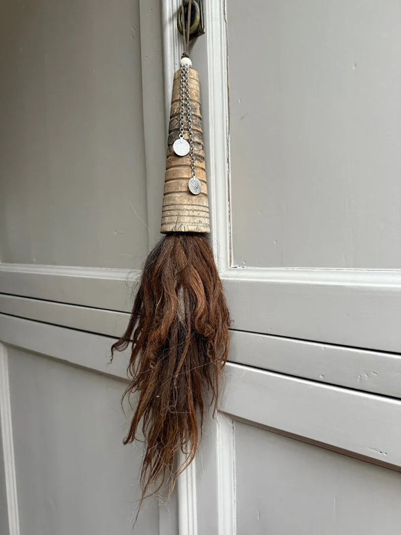 Handgemaakte landelijke woonaccessoire met houten top, kettingen en bruin paardenhaar, aan deur