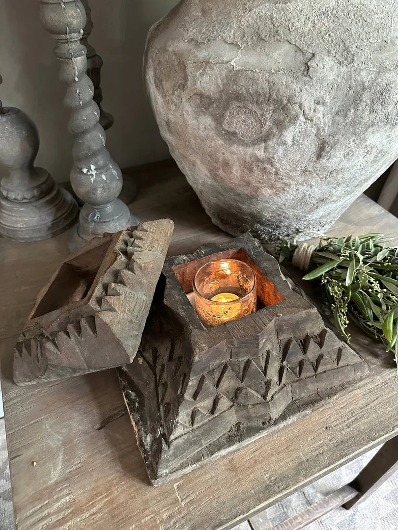 Handgemaakte houten kandelaar met kaars in sober landelijk interieur op houten tafel