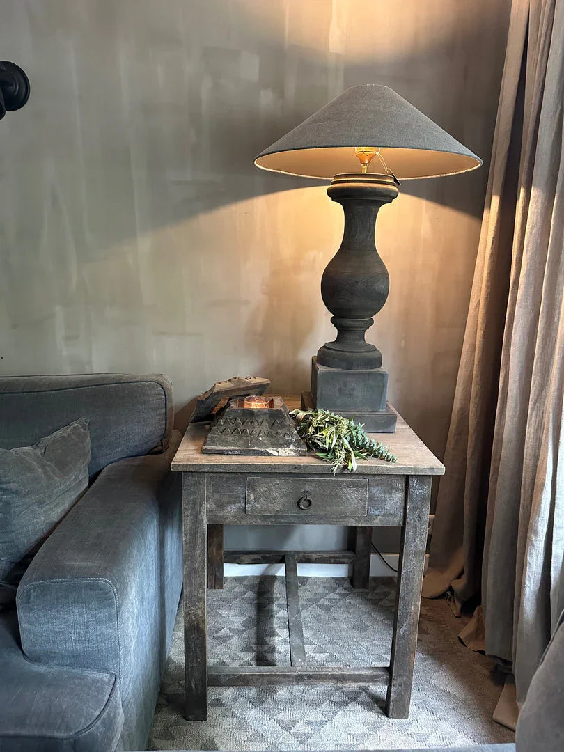 Landelijk sober interieur met grijze bank, houten bijzettafel en grote handgemaakte lamp