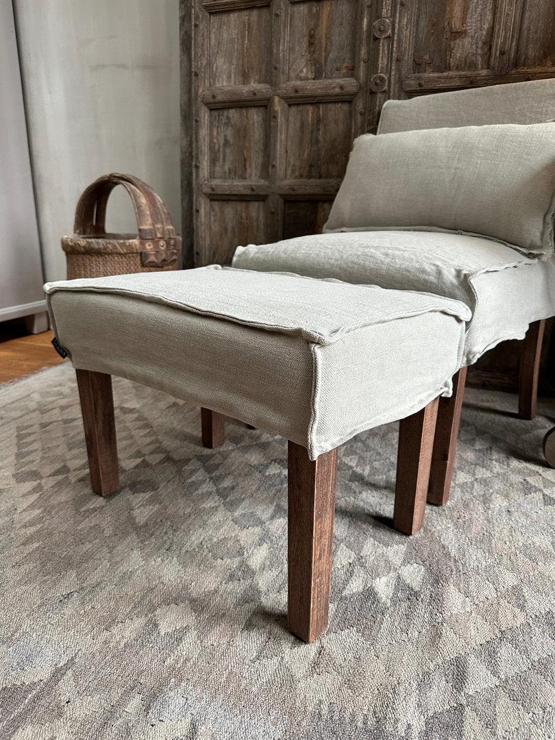 Handgemaakte landelijke fauteuil met linnen bekleding en houten poten in sober interieur bij My Sober Home