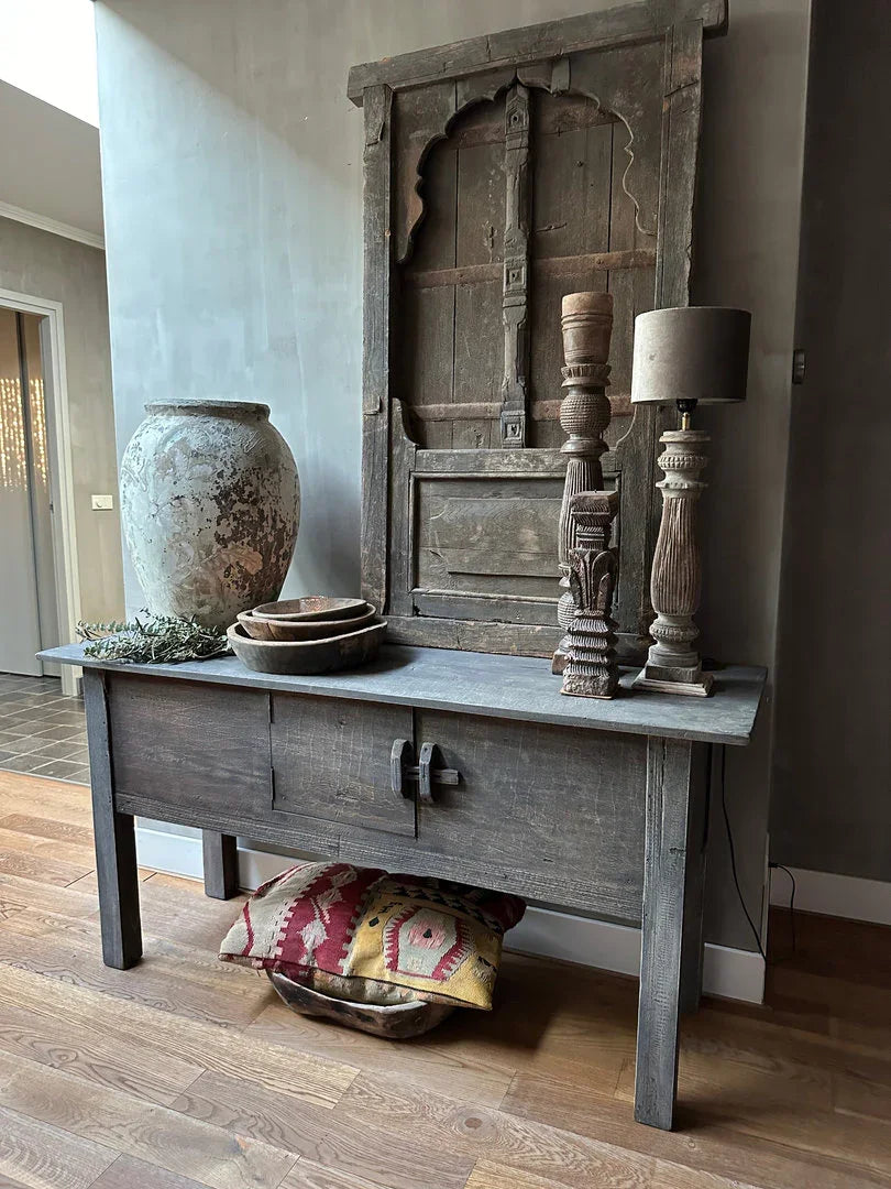 Authentieke houten sidetable met Indiase vaas, kandelaars en landelijke woonaccessoires in sober interieur