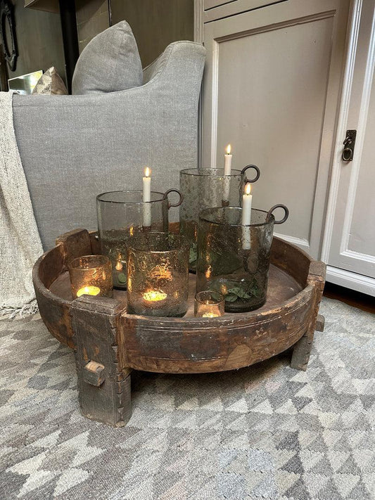 Houten schaal met rustieke glazen windlichten en kaarsen in landelijk sober interieur