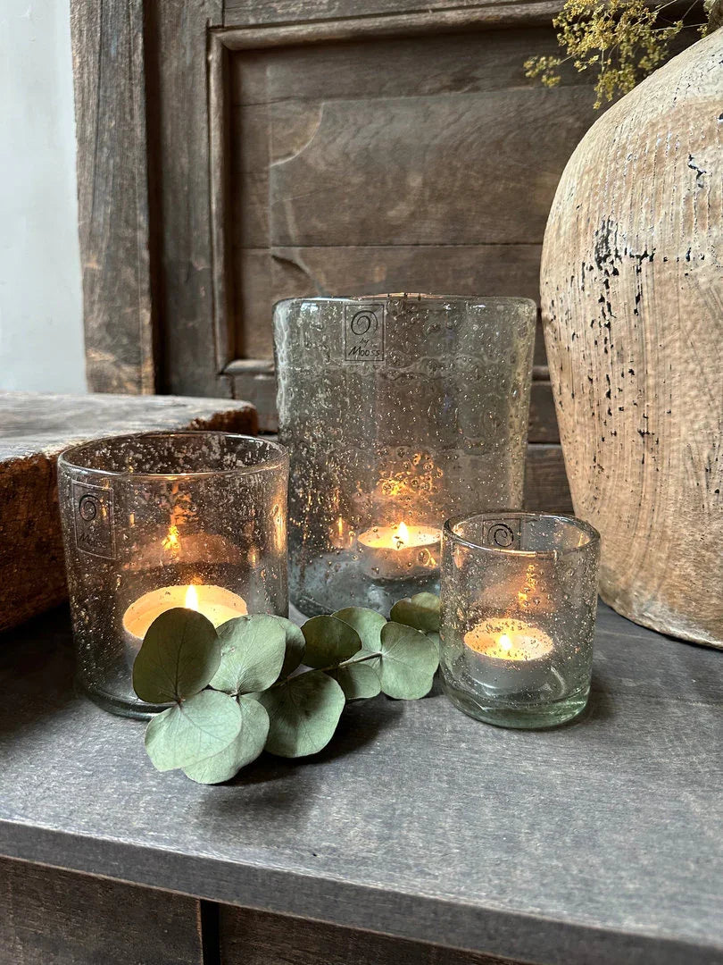 Handgemaakte landelijke theelichthouders met kaarsen en eucalyptus op houten tafel