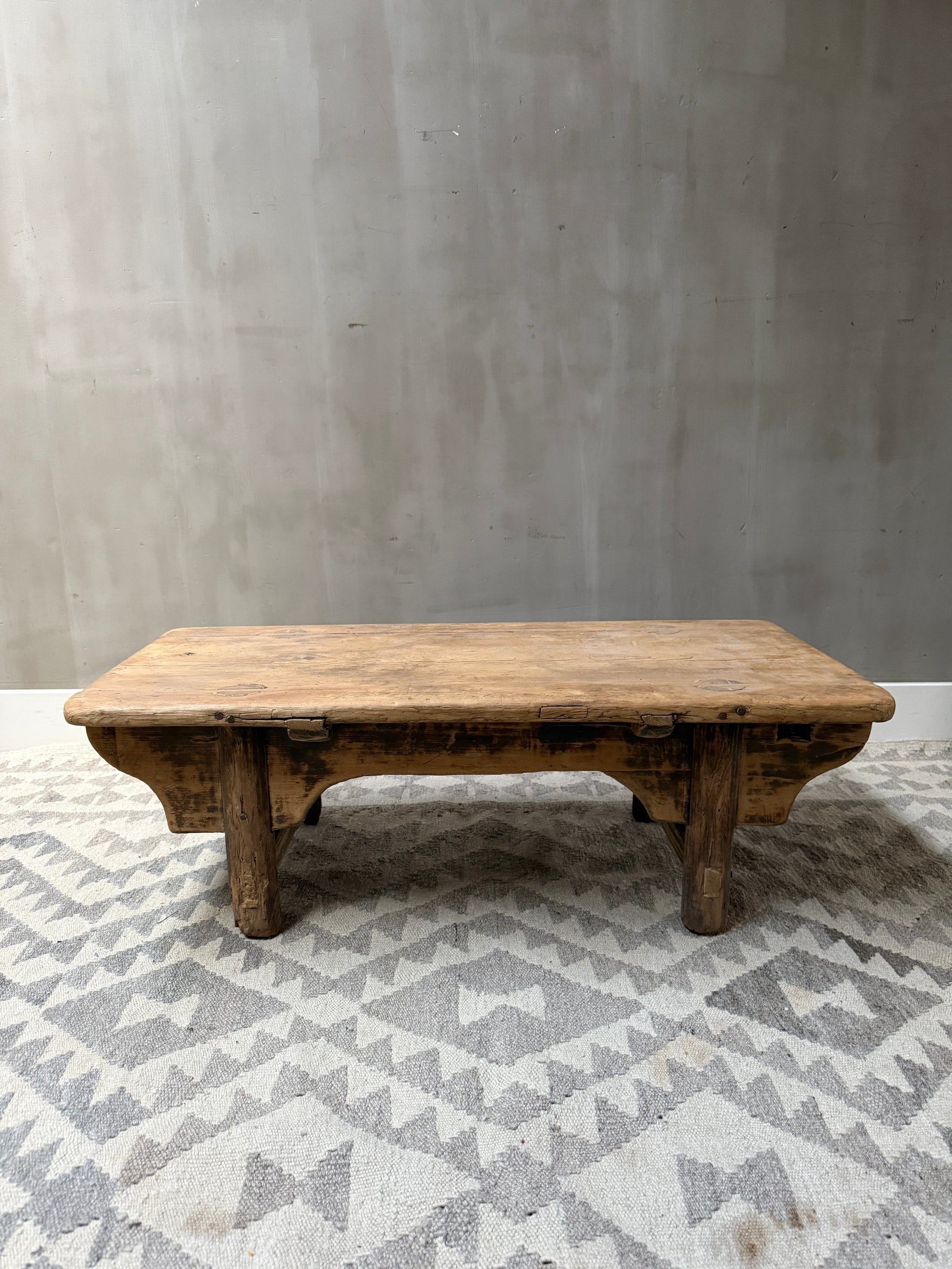 Authentieke houten kangtafel op oosters vloerkleed voor een sober, landelijk interieur