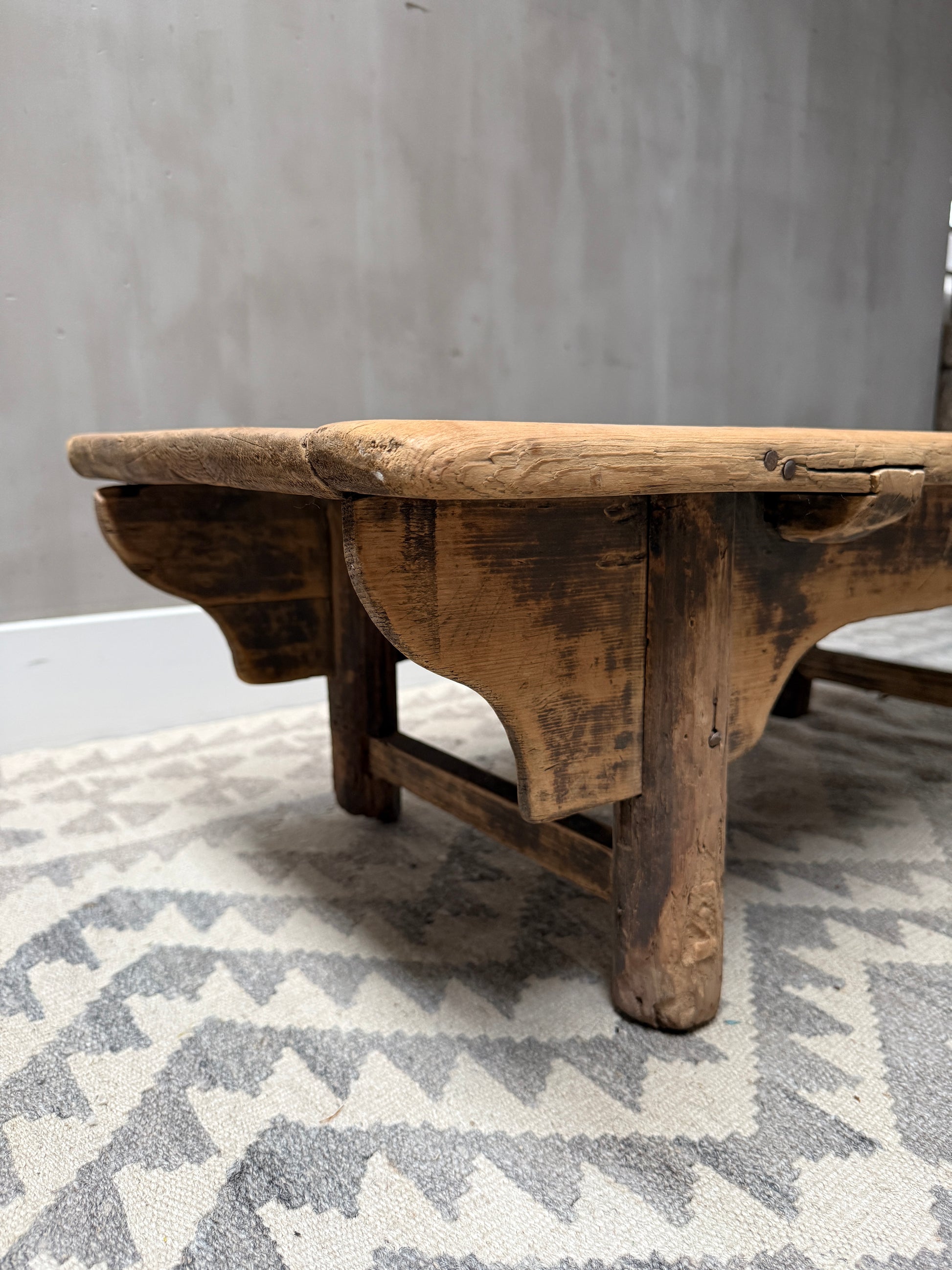 Authentieke houten kangtafel op patroonkleed, sfeervol landelijk interieur