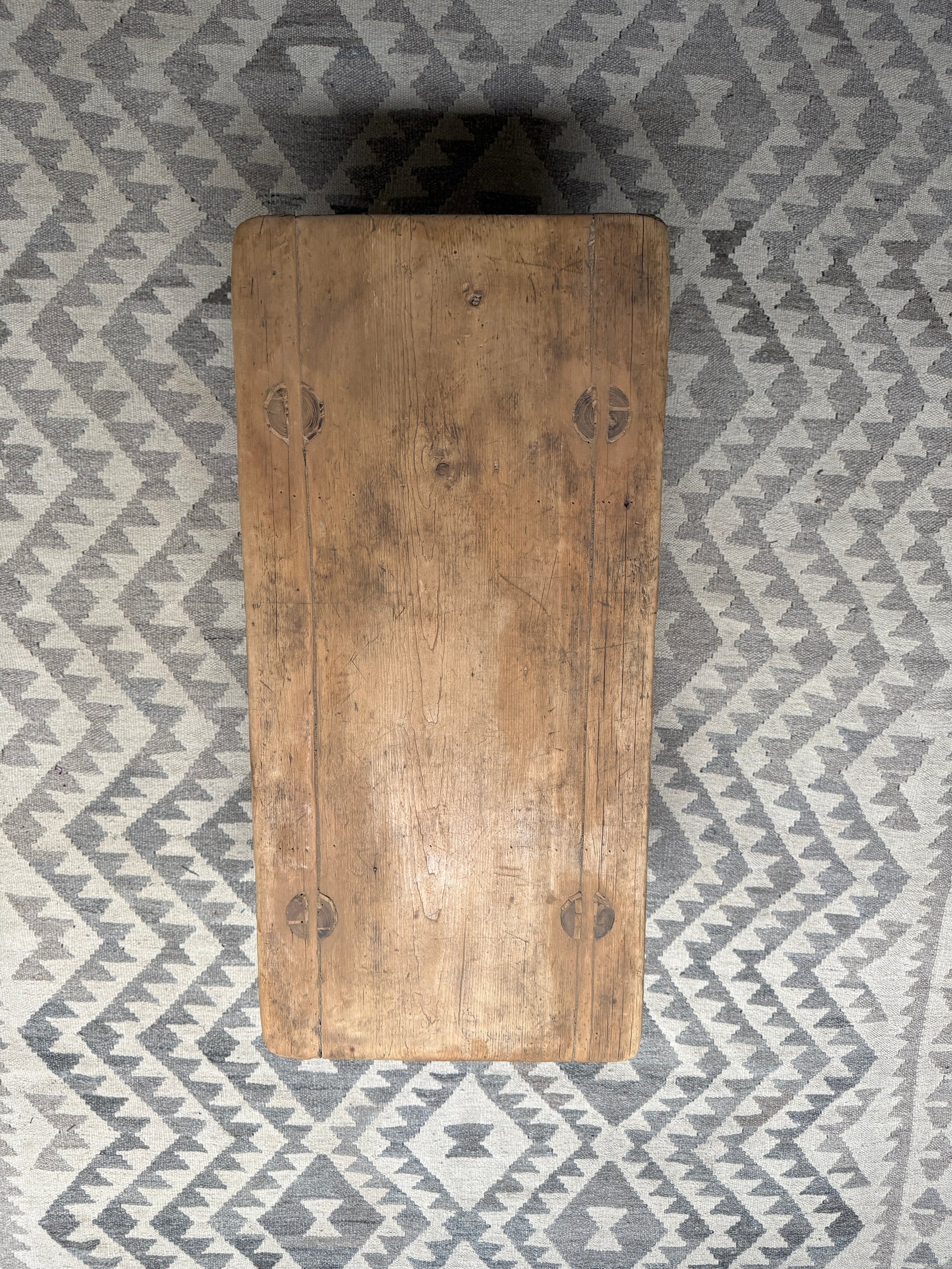 Authentieke houten bijzettafel op grijs geometrisch vloerkleed, landelijk en sober interieur