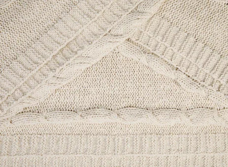 Detail van handgemaakt, beige gebreid woonaccessoire voor een sober landelijk interieur