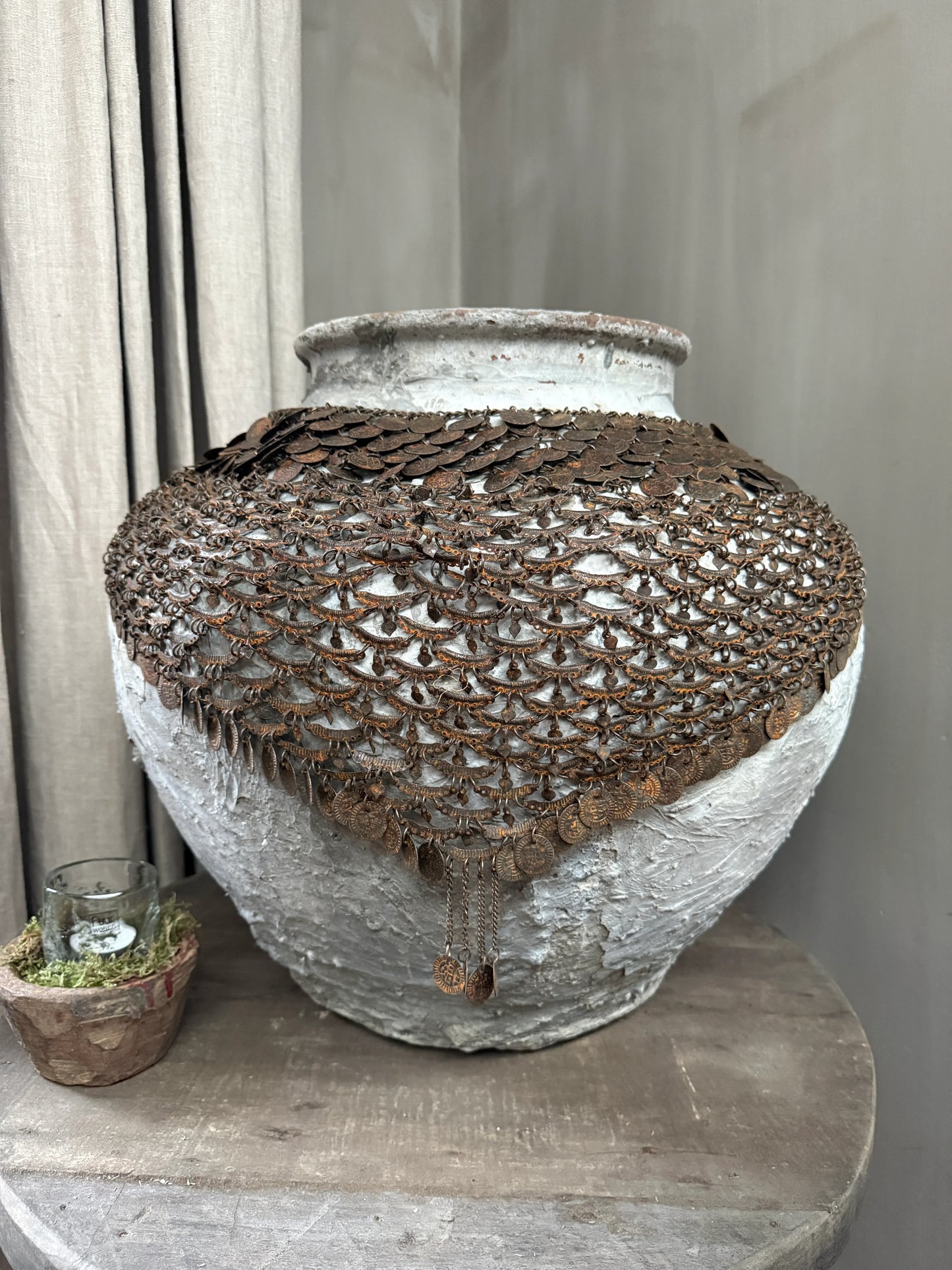 Handgemaakte kruik met vintage metalen kettingdecoratie op houten tafel, landelijk interieur