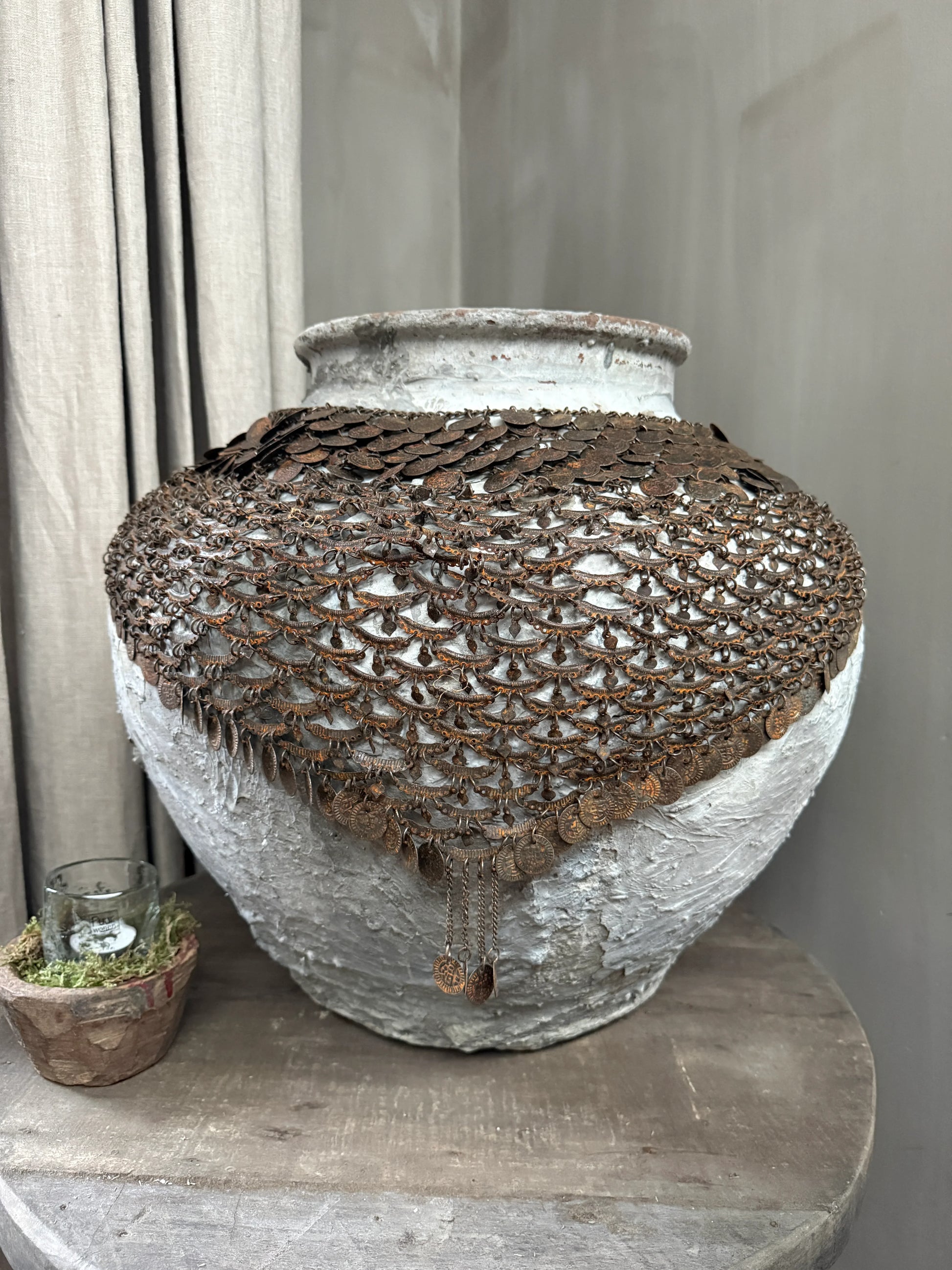Handgemaakte kruik met vintage metalen kettingdecoratie op houten tafel, landelijk interieur