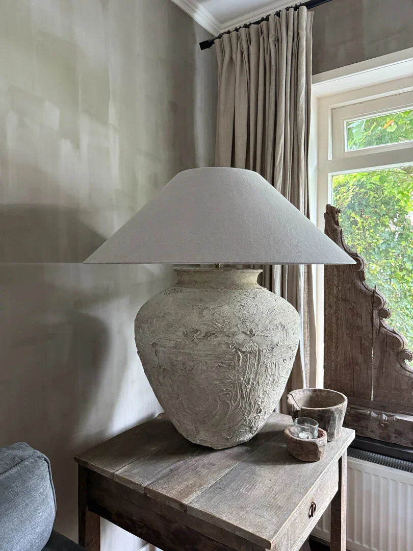 Handgemaakte kruiklamp van aardewerk op houten tafel, landelijk sober interieur