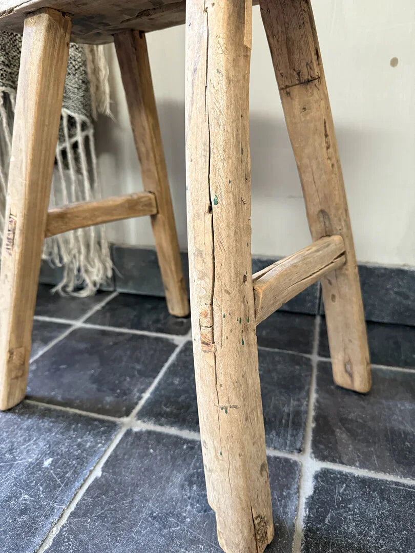 Handgemaakt houten krukje met robuuste uitstraling op grijze tegelvloer, My Sober Home woonaccessoire