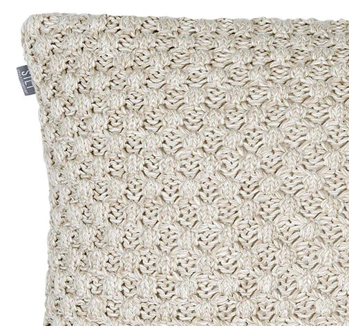 Close-up van handgemaakt beige kussen met grof breipatroon, landelijk woonaccessoire