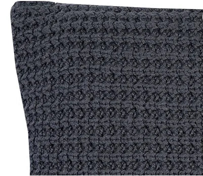 Close-up van een handgemaakt Ibiza kussen in donkergrijs, grof gebreid. Sober woonaccessoire.