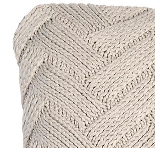 Close-up van beige gebreid sierkussen met visgraatpatroon, landelijk en handgemaakt