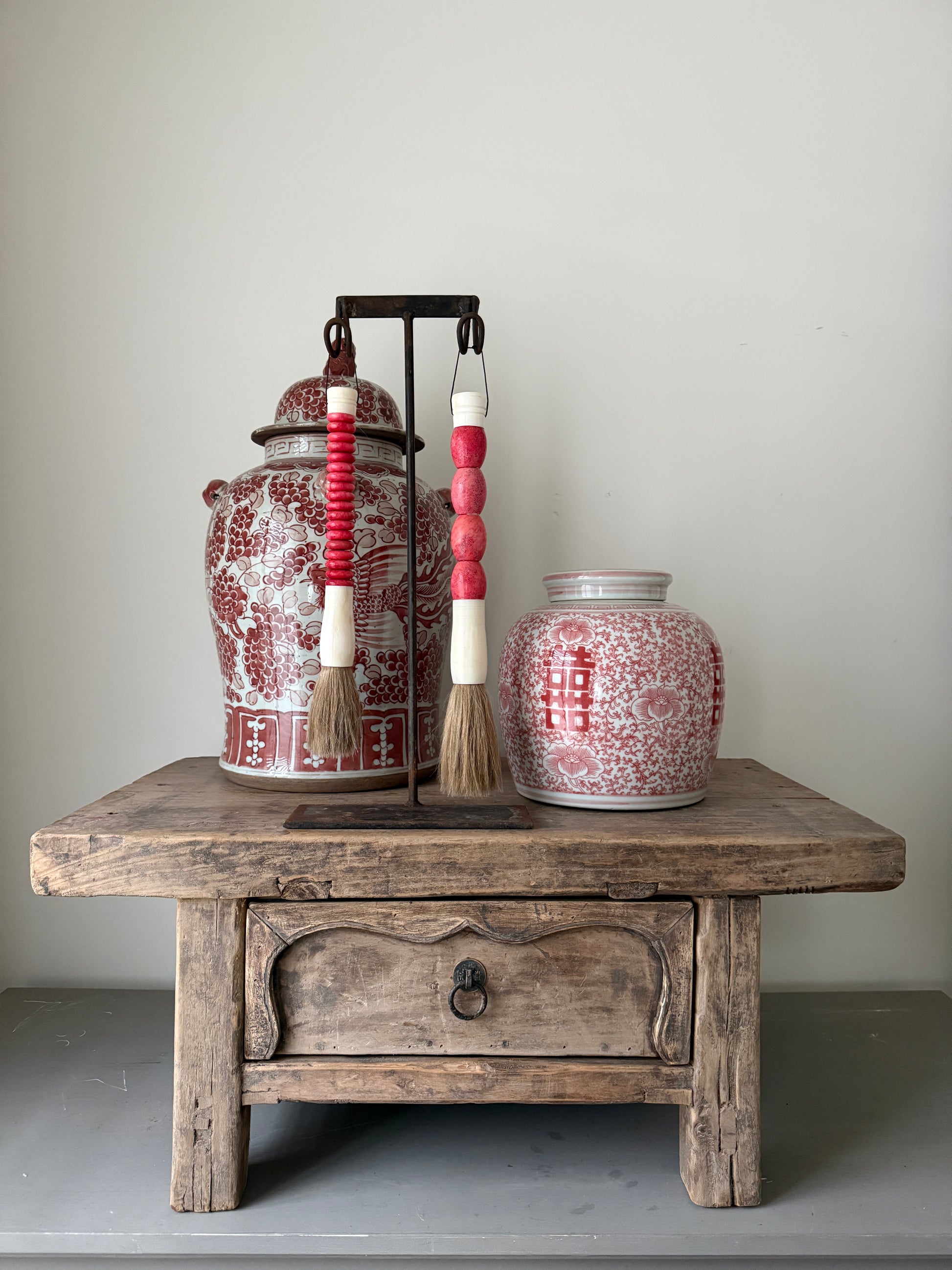 Handgemaakte kwastenset met roze kralen op houten tafel, naast Indiase en Nepalese potten, My Sober Home woonaccessoires.