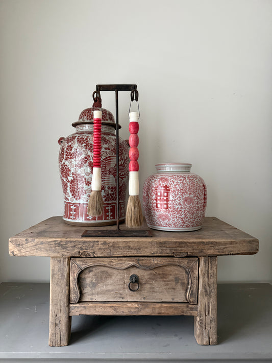 Handgemaakte kwastenset met roze kralen op houten tafel, naast Indiase en Nepalese potten, My Sober Home woonaccessoires.